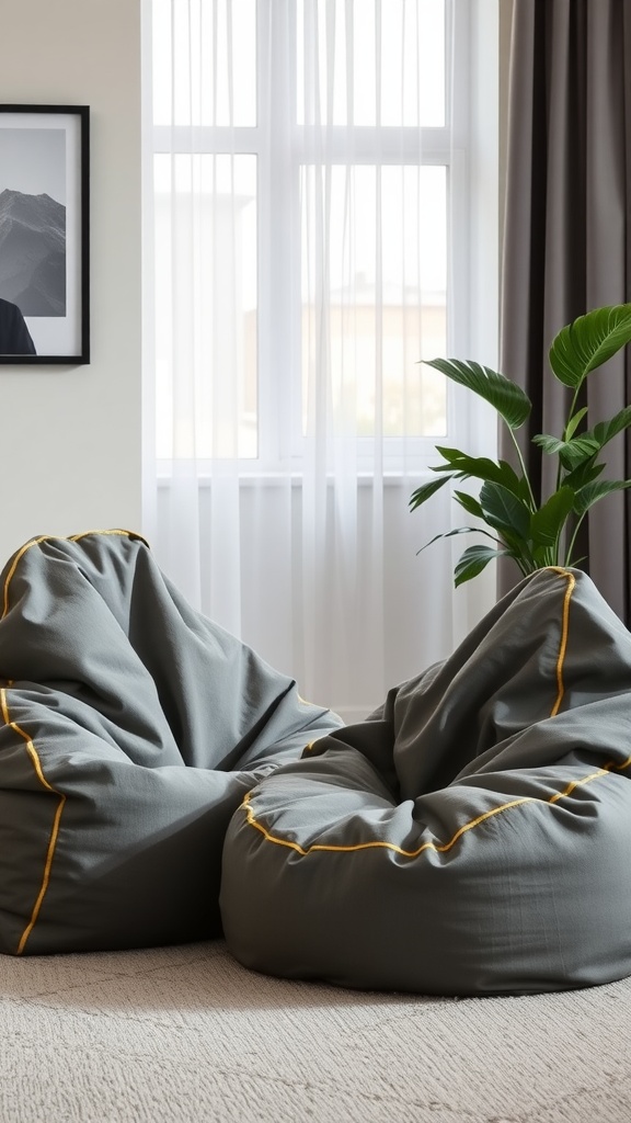 Two grey bean bags with yellow stitching next to a window with sheer curtains.